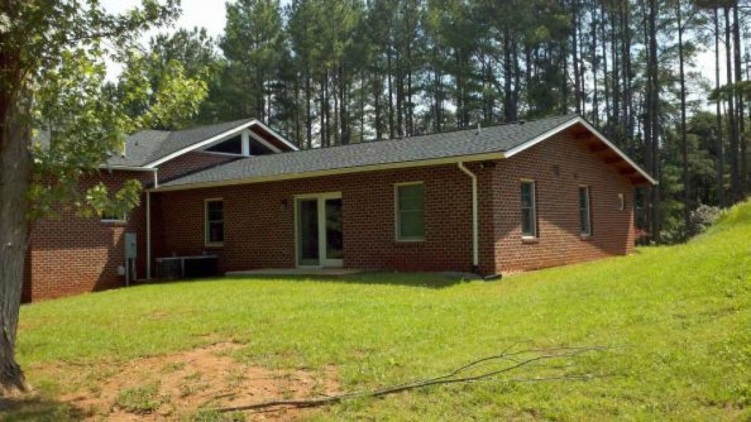 back side of brick house with sliding glass door opening onto yard lawn